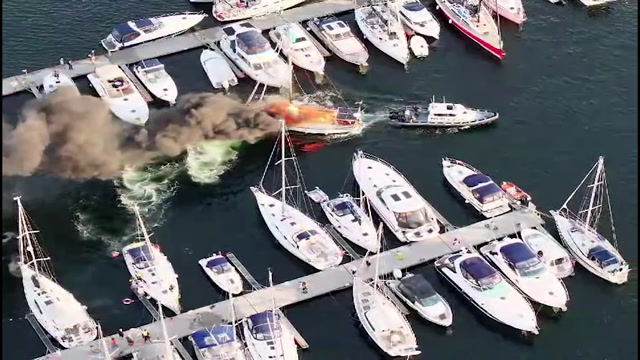 Det var mange som måtte i sving for å slukke båtbrannen i gjestehavna i Arendal. Foto: Dronefoto fra politiet