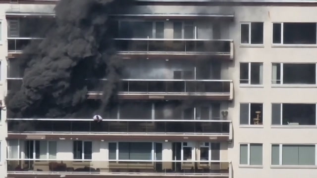 En mann reddet seg ut av den brennende boligblokka via naboens vindu. Video: AP